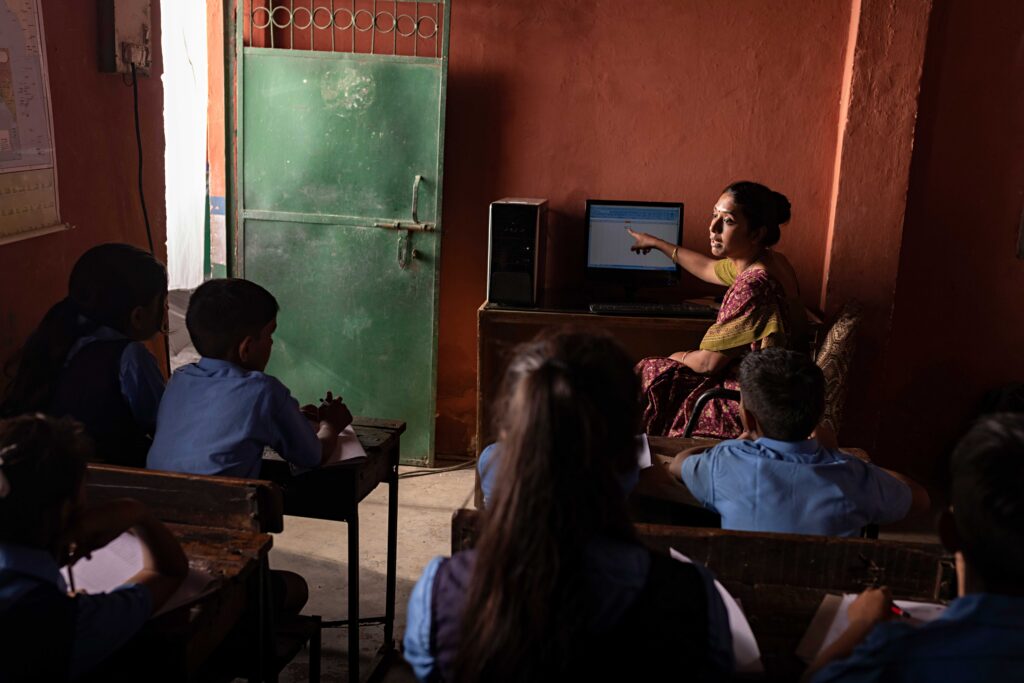 Teacher teaching students in a classroom on desktop PC.